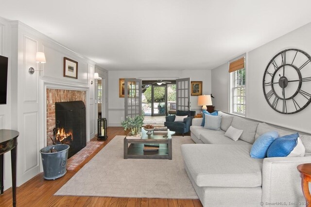 living area featuring wood finished floors, ceiling fan, and a fireplace