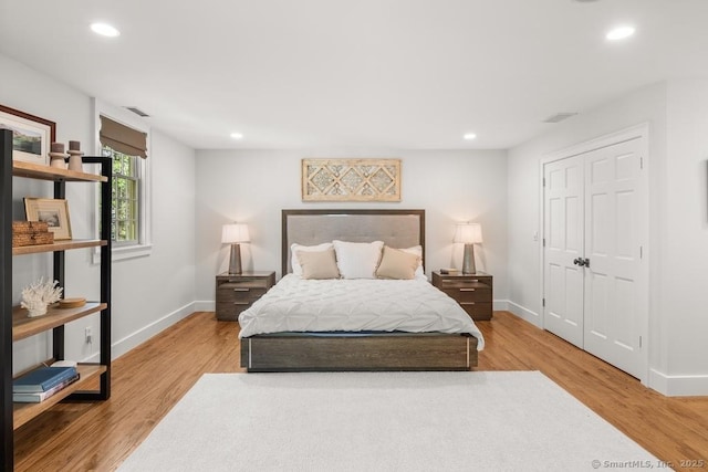 bedroom with baseboards, recessed lighting, light wood-type flooring, and a closet