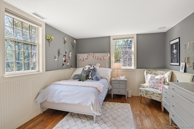 bedroom featuring wood finished floors and wainscoting