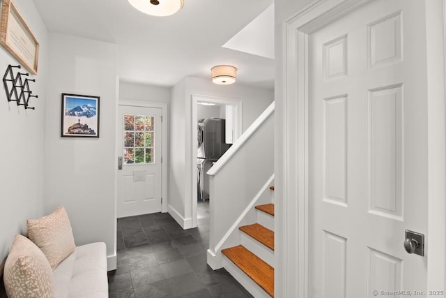 entryway with stacked washer / dryer, stairs, and baseboards