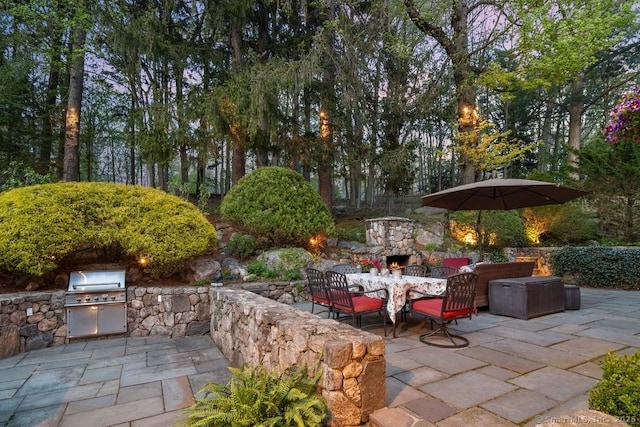 view of patio / terrace with an outdoor stone fireplace and area for grilling