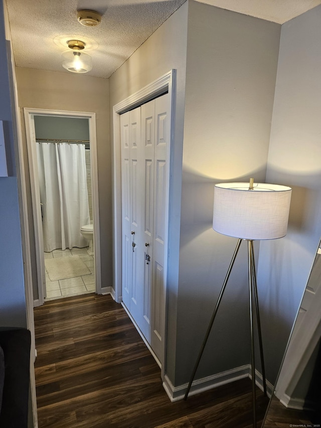 corridor with a textured ceiling and dark wood finished floors