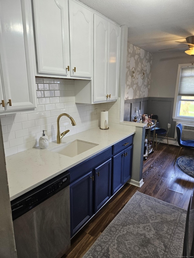 kitchen featuring stainless steel dishwasher, a sink, a wainscoted wall, white cabinets, and blue cabinets