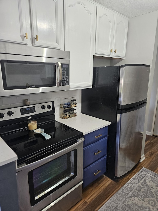 kitchen featuring dark wood-style flooring, blue cabinetry, light countertops, white cabinets, and stainless steel appliances