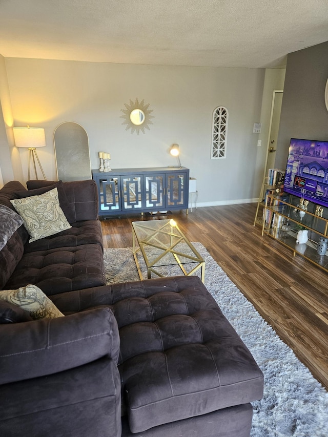 living area with baseboards, a textured ceiling, and wood finished floors