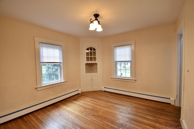 empty room with light wood-style floors, a baseboard radiator, and an inviting chandelier