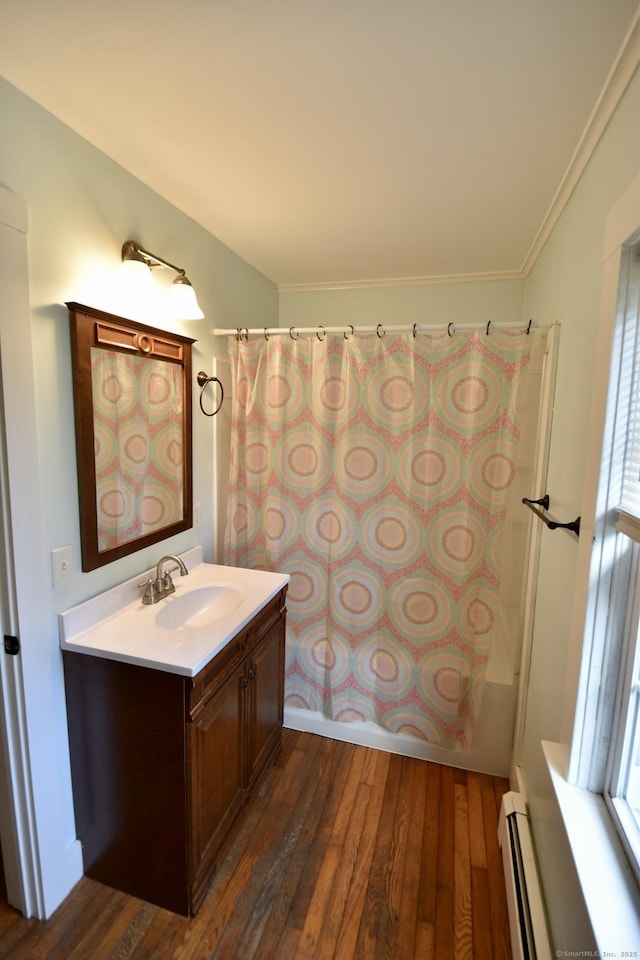 full bath featuring vanity, baseboard heating, a wealth of natural light, and hardwood / wood-style floors