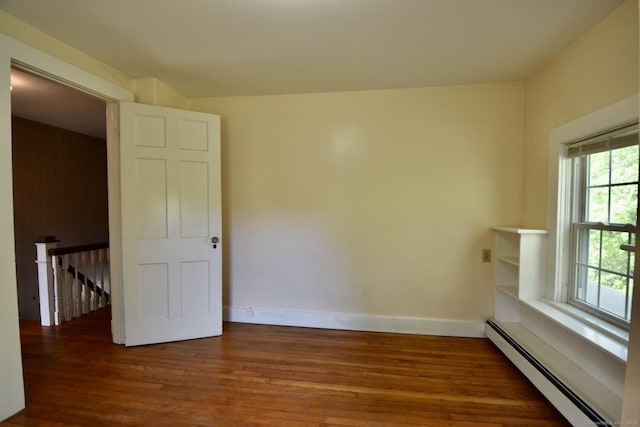 unfurnished room with baseboards, wood finished floors, and a baseboard radiator