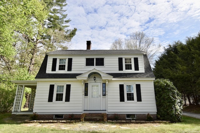 colonial inspired home with a shingled roof and a chimney