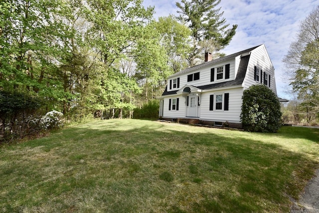view of front facade featuring entry steps, a chimney, a gambrel roof, and a front yard