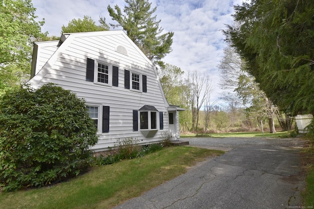 view of property exterior featuring a gambrel roof and aphalt driveway