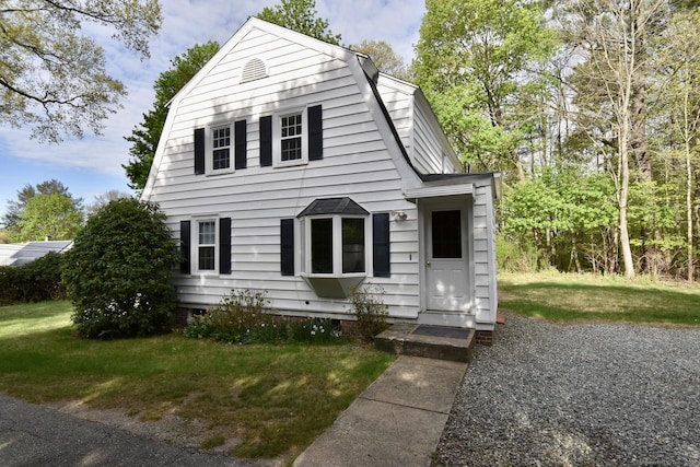 colonial inspired home with entry steps, a front lawn, and a gambrel roof