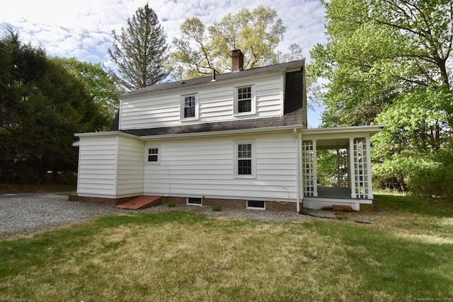 rear view of property featuring a lawn, a chimney, and roof with shingles