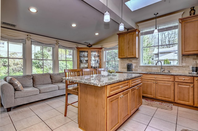1440 Straits Tpke, Middlebury, CT 06762 - kitchen with lofted ceiling with skylight, a kitchen bar, light stone counters, a sink, and light tile patterned floors