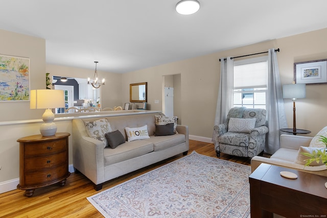 living area featuring baseboards, a chandelier, and light wood-type flooring