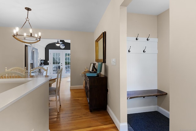interior space featuring light wood-style floors, baseboards, a chandelier, and french doors