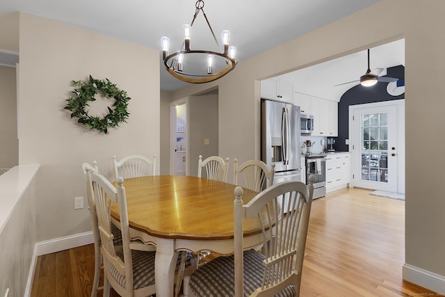 dining room with baseboards, ceiling fan with notable chandelier, and light wood-style flooring