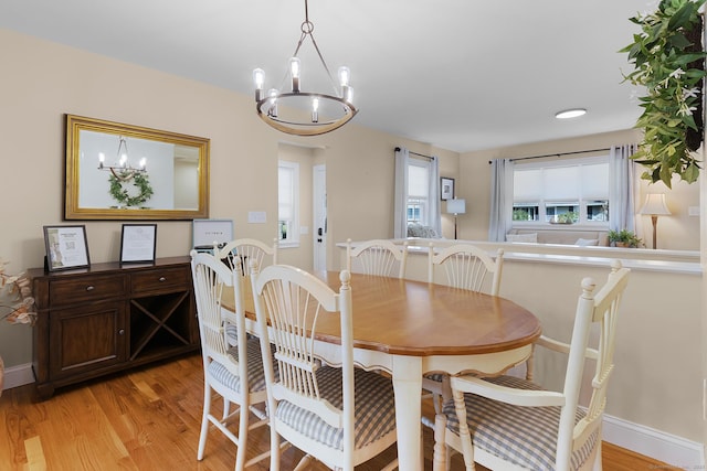 dining room with baseboards, a chandelier, and light wood-style flooring