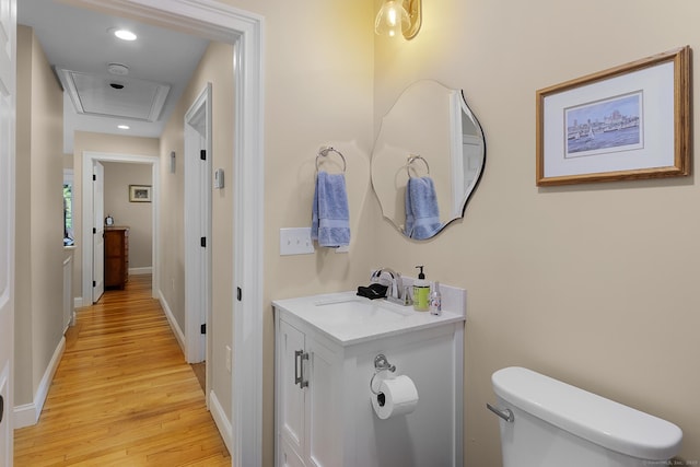 bathroom with toilet, wood finished floors, baseboards, vanity, and recessed lighting