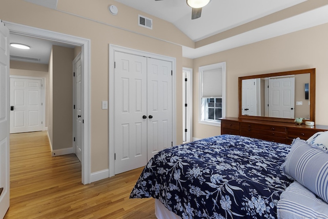 bedroom featuring lofted ceiling, a closet, visible vents, light wood-style flooring, and a ceiling fan