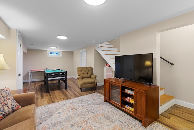 living room featuring wood finished floors, baseboards, and stairs