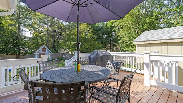 deck with a storage shed, outdoor dining space, an outdoor structure, a fenced backyard, and grilling area