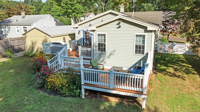 back of property with a fenced backyard, a gate, a wooden deck, and a yard