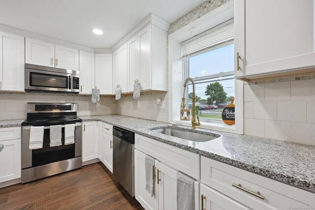 38 Broad St, Plainville, CT 06062 - kitchen featuring appliances with stainless steel finishes, white cabinets, a sink, dark wood-type flooring, and tasteful backsplash