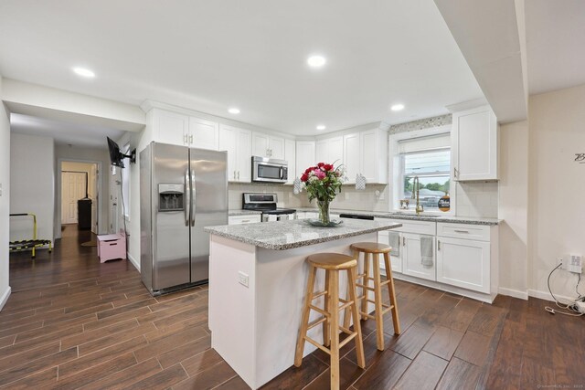38 Broad St, Plainville, CT 06062 - kitchen with stainless steel appliances, dark wood-style floors, white cabinetry, backsplash, and a kitchen island