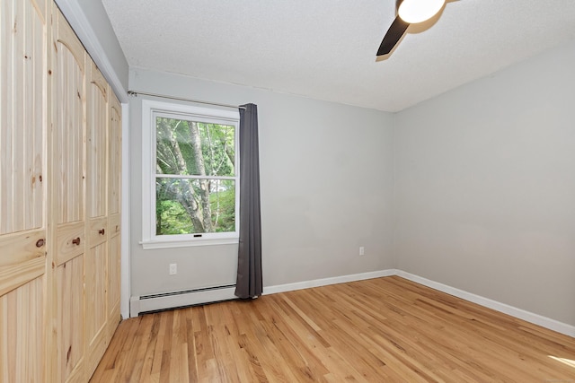 unfurnished bedroom with a closet, a baseboard radiator, light wood finished floors, and baseboards