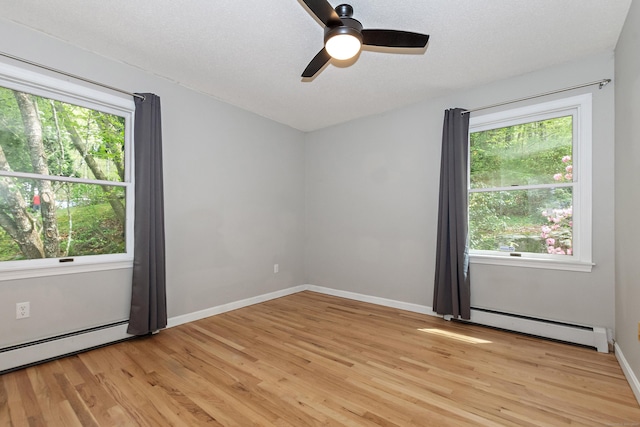 spare room with a healthy amount of sunlight, baseboard heating, and light wood finished floors