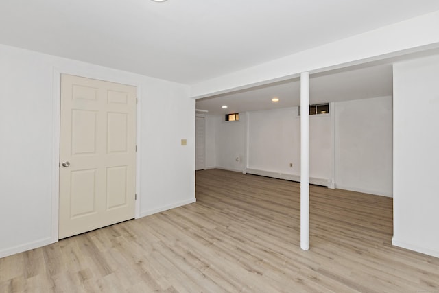 finished below grade area featuring light wood-style floors, a baseboard radiator, baseboards, and recessed lighting
