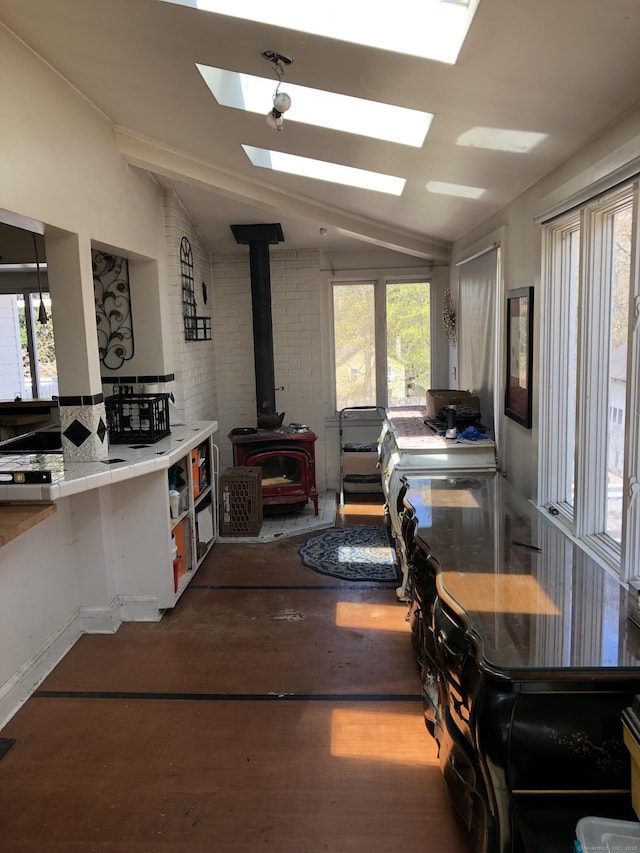 interior space featuring lofted ceiling with skylight, wood finished floors, and a wood stove