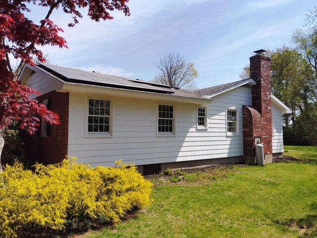 144 Fiesta Hts, Meriden, CT 06451 - view of property exterior with a lawn, roof mounted solar panels, and a chimney