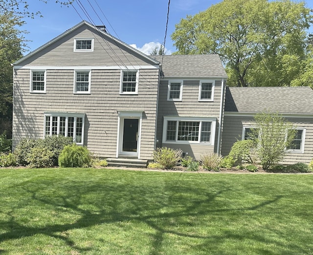 view of front facade featuring roof with shingles and a front yard