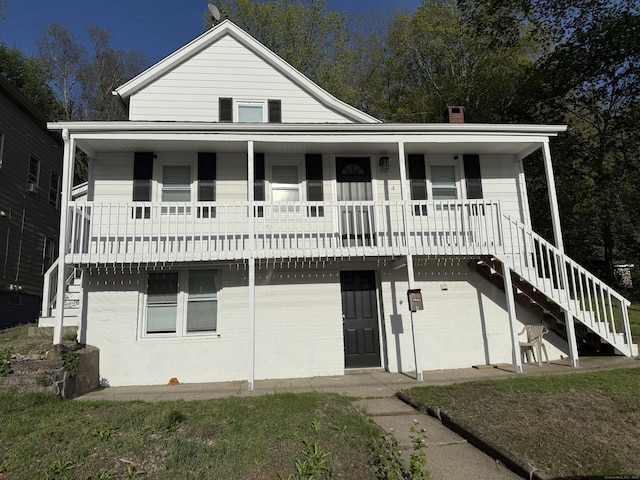 view of front of property with a porch, a chimney, and stairs