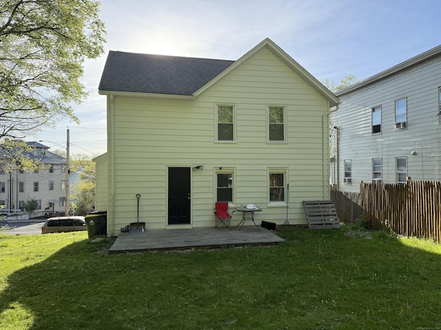 back of house with fence, a shingled roof, and a yard