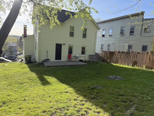 back of property with fence, a chimney, and a yard