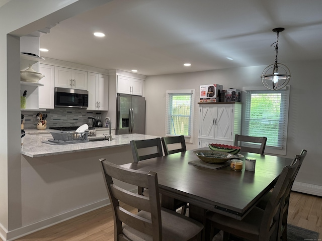 dining room featuring light wood-style floors, baseboards, recessed lighting, and a wealth of natural light