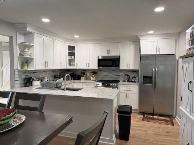 kitchen featuring a sink, white cabinetry, a peninsula, and stainless steel appliances