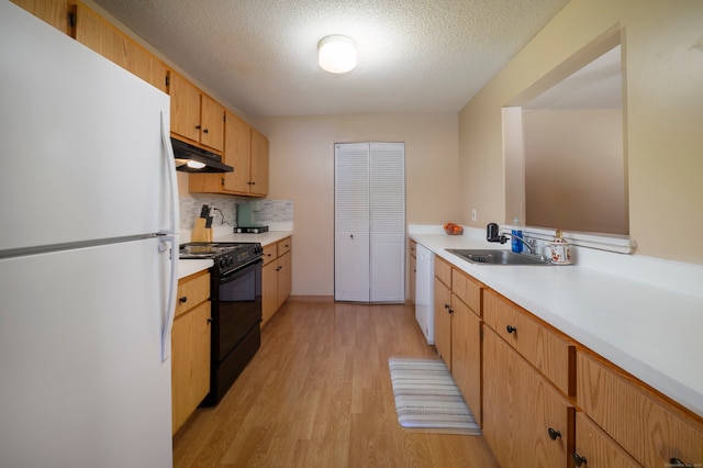 kitchen with tasteful backsplash, light countertops, light wood finished floors, under cabinet range hood, and white appliances