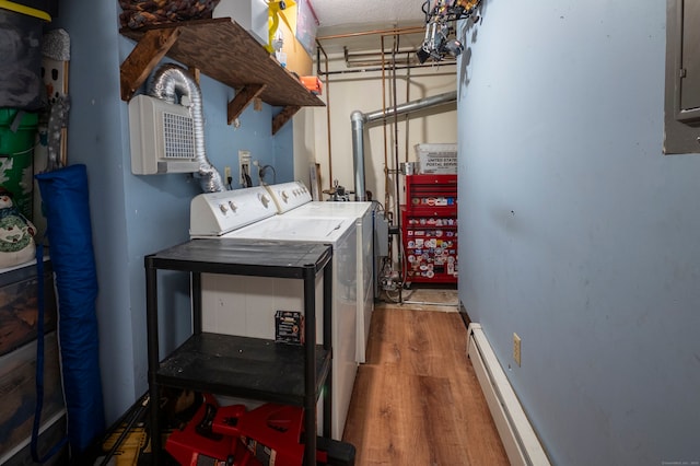 washroom with electric panel, laundry area, wood finished floors, a baseboard radiator, and washer and dryer