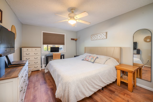 bedroom featuring dark wood-type flooring, a ceiling fan, and a textured ceiling