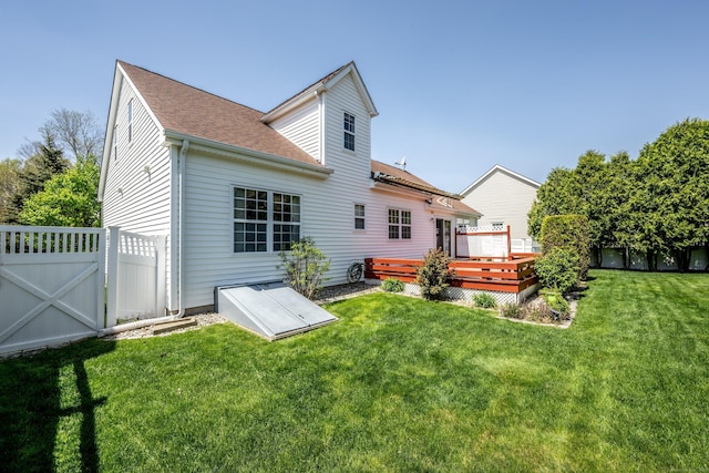 rear view of house with a wooden deck, fence, roof with shingles, a gate, and a yard