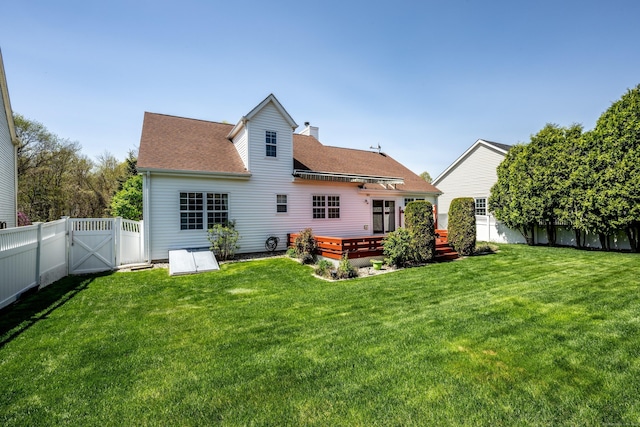 rear view of house with a wooden deck, a fenced backyard, a chimney, a gate, and a lawn