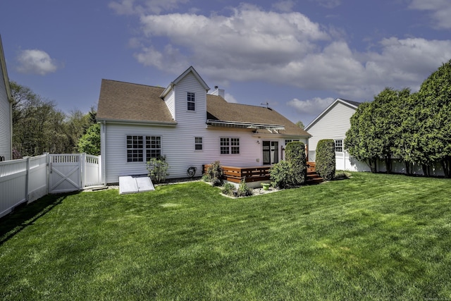 rear view of house with a shingled roof, a deck, a fenced backyard, a gate, and a yard