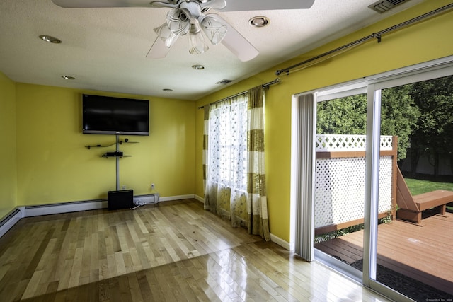 interior space featuring wood-type flooring, visible vents, baseboards, a baseboard heating unit, and a ceiling fan