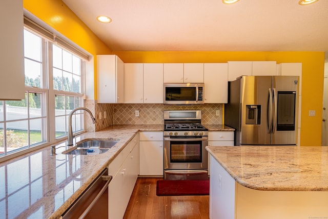 kitchen featuring white cabinets, dark wood-style flooring, light stone countertops, appliances with stainless steel finishes, and a sink