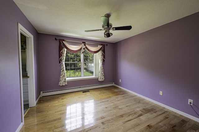 spare room featuring a textured ceiling, a baseboard heating unit, and wood finished floors