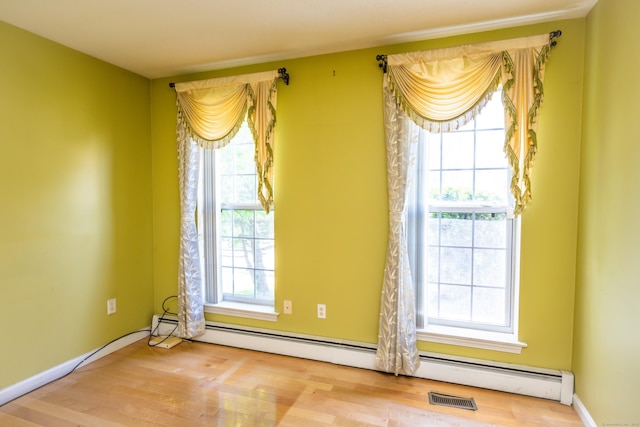 interior space with a baseboard heating unit, visible vents, and wood finished floors